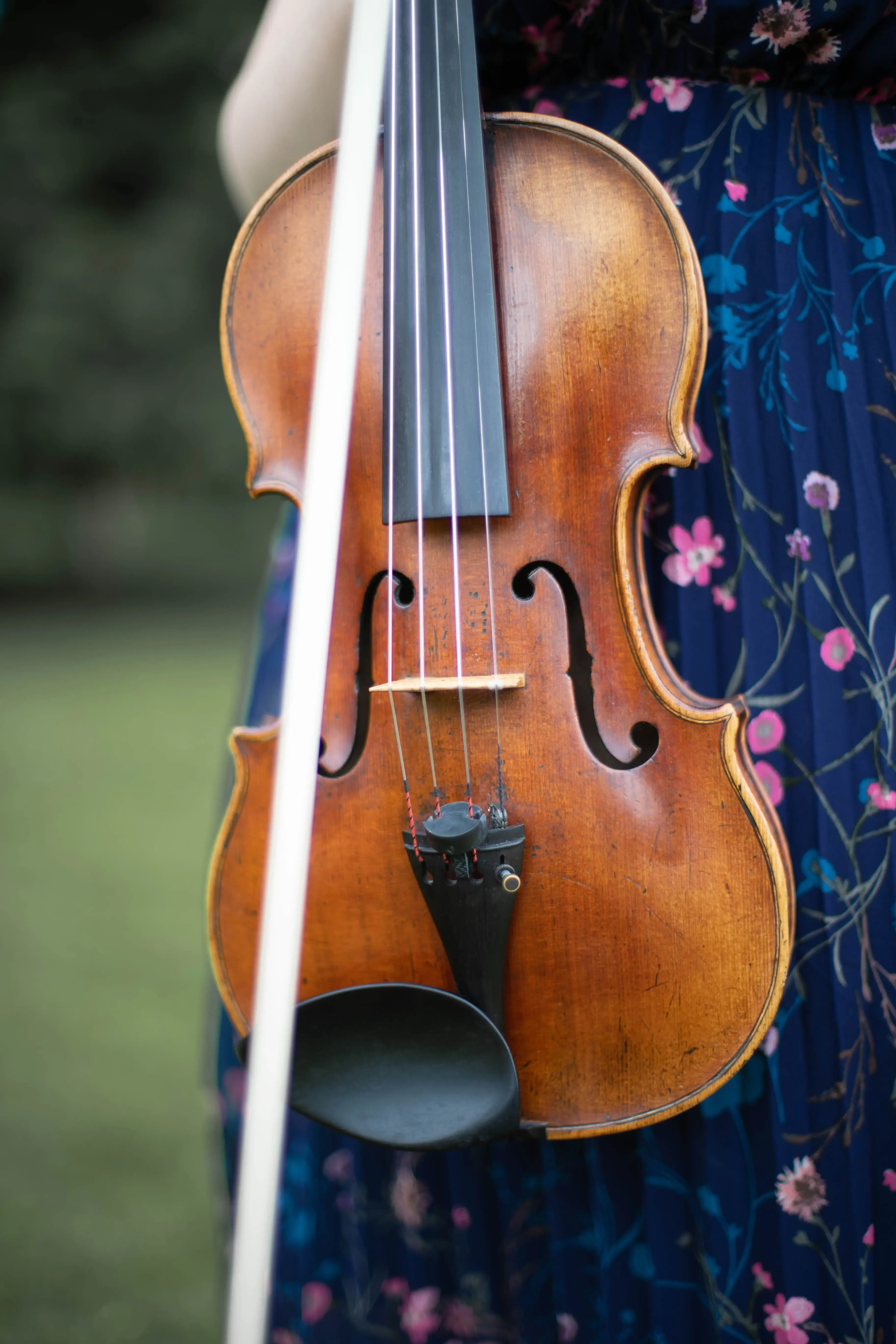 image of violin with violinists blue flowery dress in background