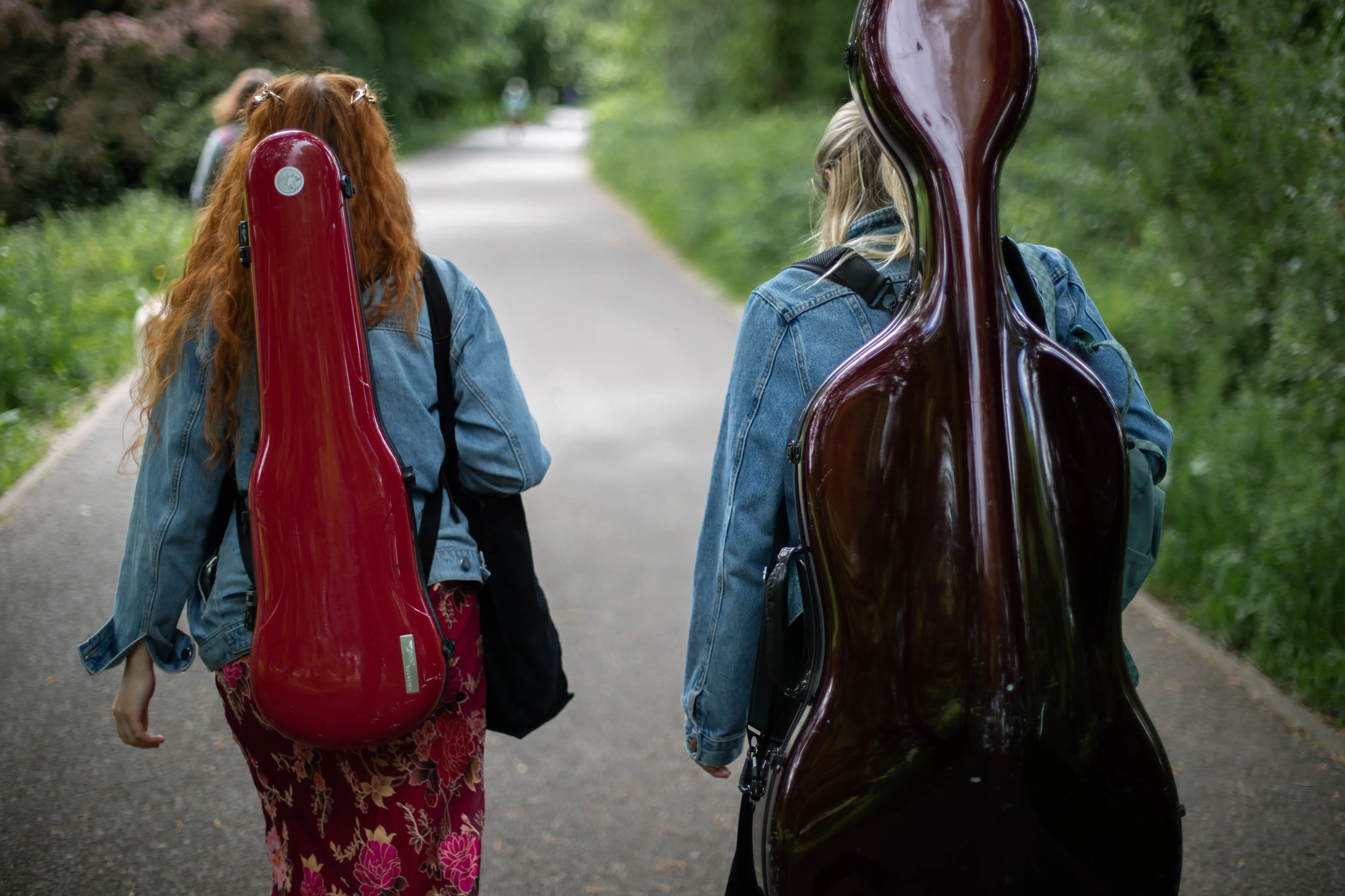 image of cellist and violinist walking. image taken from behind.